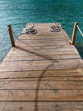 Gölgeler gün batımında ahşap iskelede kesiliyor. Denizin üzerinde güzel bir manzarası olan iskele.