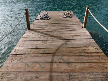 Gölgeler gün batımında ahşap iskelede kesiliyor. Denizin üzerinde güzel bir manzarası olan iskele.