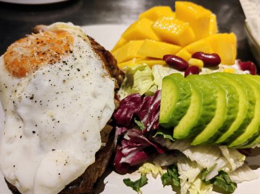 Ana yemek yumurta, avokado ve kuru domates ve bir kase yoğurt, mango, kestane ve kahve tozu. Avokado dilimleri, kuru domatesler ve tatlı olarak bir kase yoğurt, mango, kestane ve kahve tozundan yapılmış sağlıklı bir yemek..