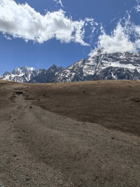 Karla kaplı dağ yolu, temiz hava ve yeşil otlarla dolu doğa manzarası.