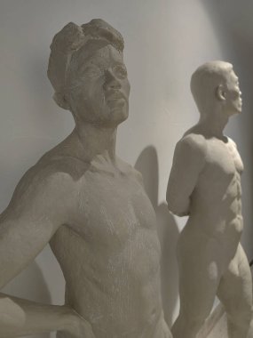 Sanat okulu eğitimi ve güzel sanatlar yüksek lisansı. Sanat ve heykel. Beyaz duvar arkaplanındaki atölyede alçı taşı pozu veren sanatçı.