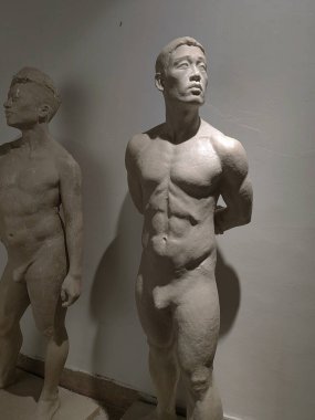 Sanat okulu eğitimi ve güzel sanatlar yüksek lisansı. Sanat ve heykel. Beyaz duvar arkaplanındaki atölyede alçı taşı pozu veren sanatçı.