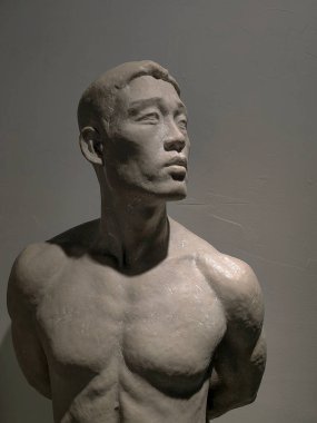 Sanat okulu eğitimi ve güzel sanatlar yüksek lisansı. Sanat ve heykel. Beyaz duvar arkaplanındaki atölyede alçı taşı pozu veren sanatçı.