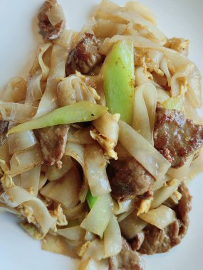 Sebzeli ve biftekli Wok tabak Asya spagettisi. Tahta masadaki beyaz kase, yukarıdan vurulmuş. yiyecek sağlıklı