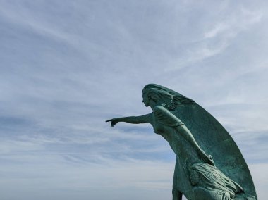Bronz bir kadın heykeli ve kızı gökyüzünü işaret ediyor, oksit yeşili renkler içinde.