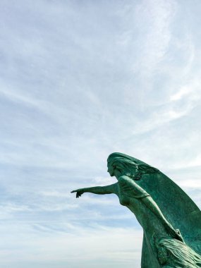 Bronz bir kadın heykeli ve kızı gökyüzünü işaret ediyor, oksit yeşili renkler içinde.