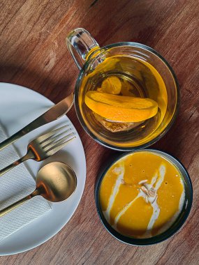 Krema desenli baharatlı baharatlı ve kızarmış balkabağı kremalı çorba. Çatal bıçakla beyaz sofra takımında servis edilir..