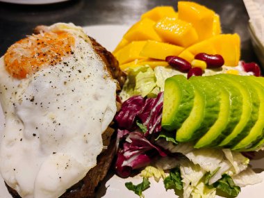 Ana yemek yumurta, avokado ve kuru domates ve bir kase yoğurt, mango, kestane ve kahve tozu. Avokado dilimleri, kuru domatesler ve tatlı olarak bir kase yoğurt, mango, kestane ve kahve tozundan yapılmış sağlıklı bir yemek..