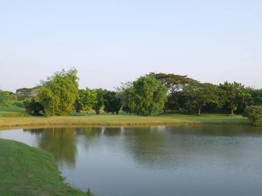 Surabaya, Endonezya; 9 Temmuz 2021: Yeşil, göl, binalar ve ağaçlı golf sahası