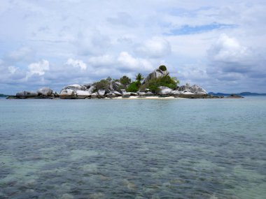 Güzel tropikal plaj, ada, kayalar ve bitki örtüsüyle.