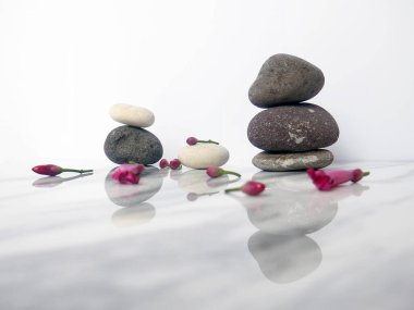Zen çakıl taşları ve çiçekler. Taş kaplıca ve sağlık sigortası konsepti. Beyaz mermer bir zeminde izole edilmiş.