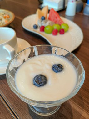 Üstünde yaban mersini ve meyve salatası olan bir fincan peynirli kek..