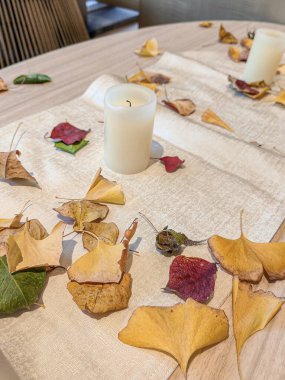 Sonbahar tonları ve yaprakları, çiçek ve mum yemek masası için idealdir..
