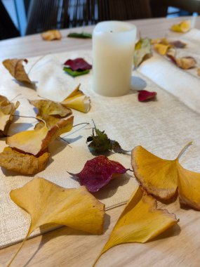 Sonbahar tonları ve yaprakları, çiçek ve mum yemek masası için idealdir..