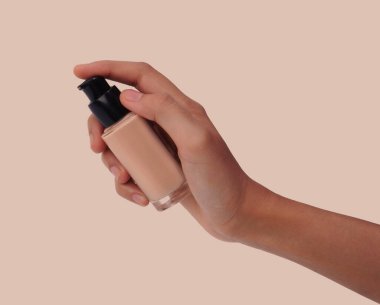 Elinde pompa kutusuyla sıvı bir vakıf şişesi tutarken, arka planda izole edilmiş.