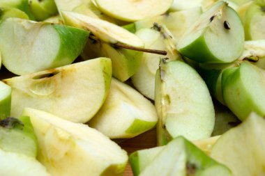 Detaylı bir yakın plan, görünür çekirdekleri ve çekirdekleri olan taze, açık yeşil elma dilimlerini gösterir.