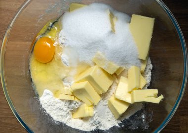 Pasta için un, şeker ve tereyağı içeren bir kase malzeme. Kase ahşap bir masanın üzerinde. Tablo üstü görünümü