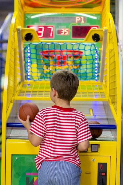 Entertainment center and children\'s area with slot machines. boy throws basketball in basket. Basketball arcade game.