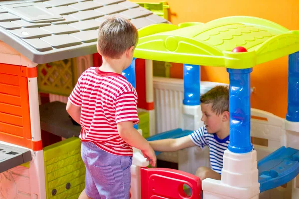 Children play in indoor playground. Two boys playing with colored toy houses