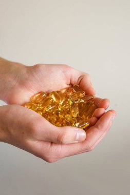Bir insan büyük miktarda altın kapsül bulundurur, vitaminleri, takviyeleri ve sağlığı temsil eder.