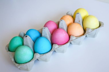 Paskalya ve bahar şenliklerini simgeleyen gri bir kutuya yerleştirilmiş parlak boyalı yumurtalar.