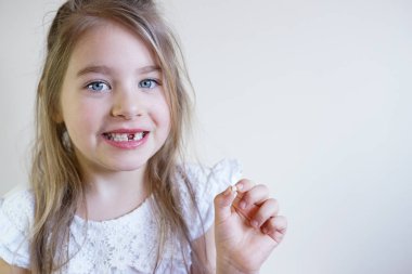 Küçük bir kız ilk dişini kaybettiği için mutlu. Büyümenin neşeli bir anı.