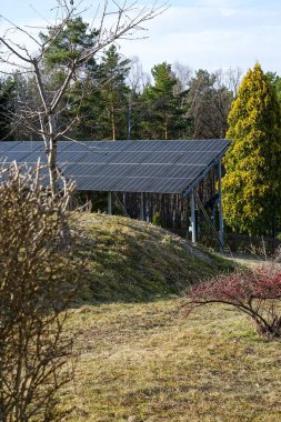 Yeşil ve ağaçlarla çevrili kırsal bir alanda, temiz enerjiyi destekleyen güneş paneli kurulumu