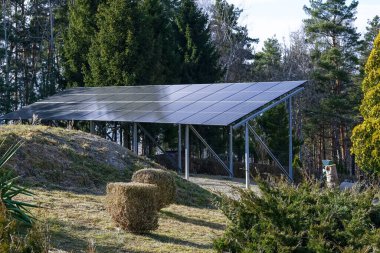 Yeşil ve ağaçlarla çevrili kırsal bir alanda, temiz enerjiyi destekleyen güneş paneli kurulumu