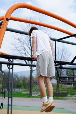 Atletik adam bir sokak idman parkında üst vücut gücünü çalıştırıyor..