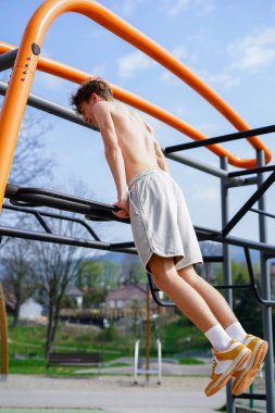 Atletik adam bir sokak idman parkında üst vücut gücünü çalıştırıyor..