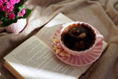 Bir fincan sıcak kahvenin, güzel bir kitabın ve huzurlu bir ortamda yumuşak marşmelovun tadını çıkar.