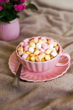 Renkli şekerlemelerle dolu sıcak bir fincan kahve tatlı ve rahat bir atmosfer yaratıyor.