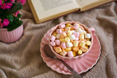 Pastel şekerlemelerle kaplı sıcak bir tatlı, kitapla sıcak bir an için mükemmel.