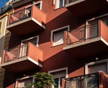 Güzel, canlı, modern bir apartman cephesinde balkonlar ve yumuşak ışıkta parlayan büyüleyici gölgeler sergileniyor.