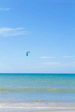 Man practicing kite surfing in the sea, doing sport. Sea and blue sky. Beautiful sunny day clipart