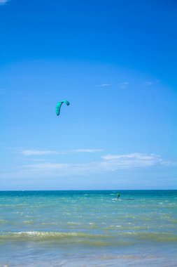 Beautiful sunny summer day and athlete practicing kite surfing in the blue sea. clipart