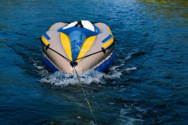Renkli bir çocuk kanosu nehir boyunca çekiliyor ve dalgalar yaratıyor.