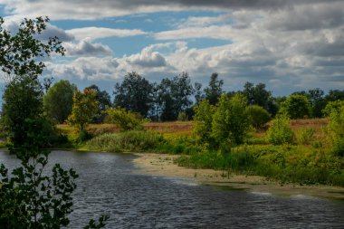Aşırı gelişmiş nehir kıyısı ve renkli bulutlu gökyüzü ile yaz fantezi manzarası