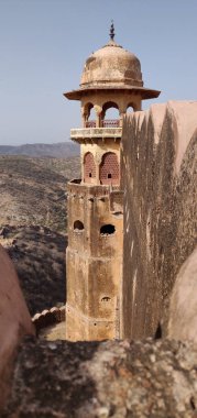 A tall tower with a dome on top. The tower is in a desert hillside and has a lot of cracks in it clipart