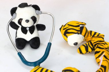 Plush panda with stethoscope examining a tiger stuffed toy - pediatric care or playful veterinary concept, isolated on white background. clipart