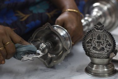 Close-up of hands polishing traditional silverware, featuring intricate Hindu deity design. Perfect for themes of craftsmanship, culture, tradition, and artisan work. clipart