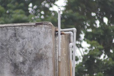 Close-up of a weathered concrete wall with visible water leakage stains and rusted pipe fittings, highlighting issues of poor drainage or maintenance. Ideal for illustrating construction, plumbing, or urban infrastructure problems. clipart