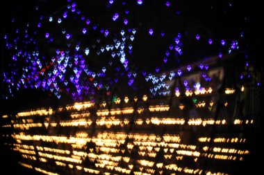 Mor, mavi ve altın renkli bokeh lambaları koyu bir arka planda, rüya gibi, romantik ve şenlikli bir atmosfer yaratıyor. Sevgililer günü, kutlamalar ya da sanatsal projeler için mükemmel..