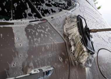 Arabayı fırça ve köpükle temizliyorum.