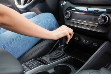 Lüks bir arabanın vites koluna genç bir kadının elini kapat. Sürücü kavramı