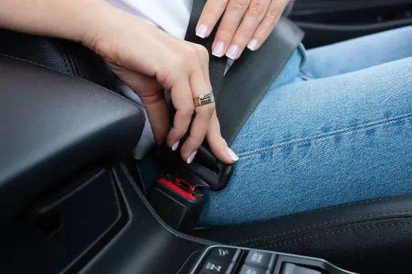 Kadın elleri arabanın emniyet kemerini bağlıyor.