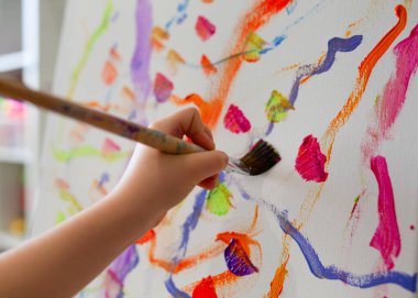 Bir çocuğun elinin fırça tutarken ve tuvale yağlı boya ya da akrilik boya sürerken yakın plan fotoğrafı. Çizim. - İnsanlar. Çocuklar için yaratıcı bir hobi. Güzel sanatlar eğitimi. Eğitim.