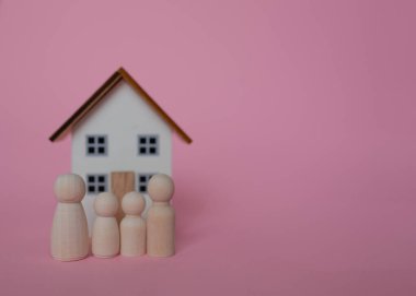 Bir çift ve bir çocuk heykeli ve pembe arka planda bir oyuncak ev.