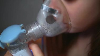 Astım spreyinin maskesindeki şirin bebek. Evde solunum prosedürü uygulanıyor. Bebek nebulizörle solunum tedavisi görüyor..
