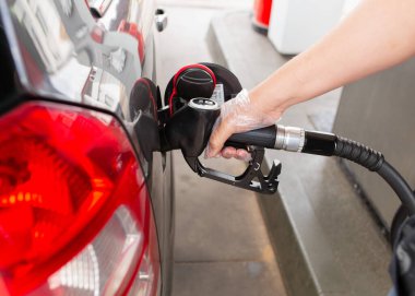 Benzin istasyonunda yakıt ikmali yapan, yakıt hortumunu tutan, ulaşım, seyahat ve enerji kullanımını sembolize eden bir adamın yakın çekimi..